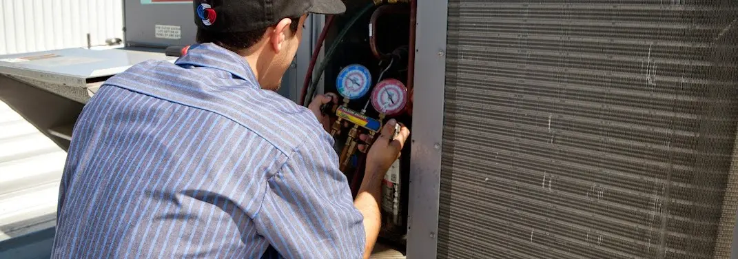 HVAC technician servicing a condenser unit in Wright City